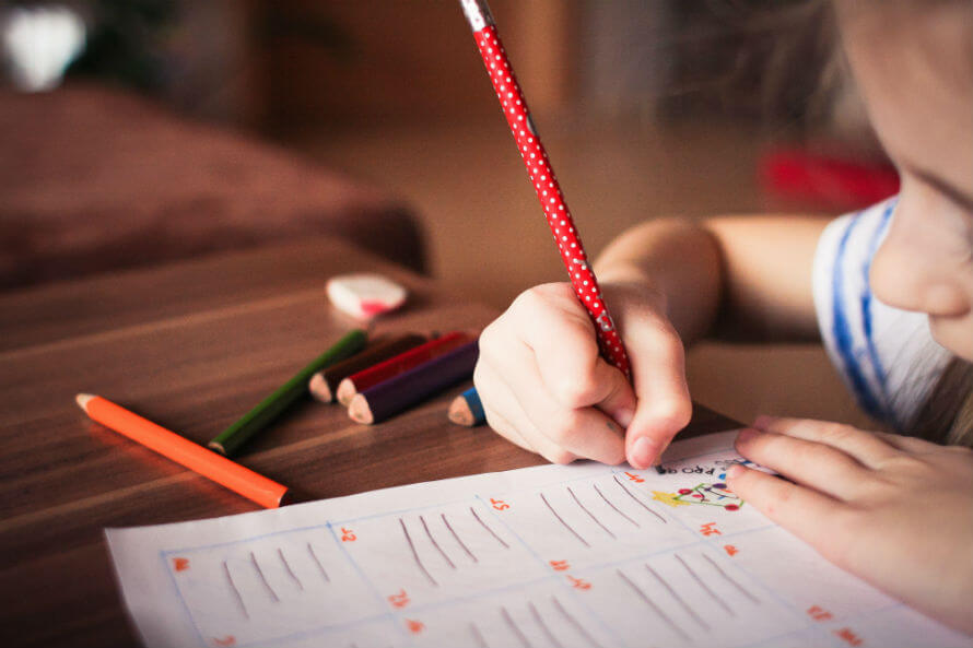 A young girl at school writing in a workbook