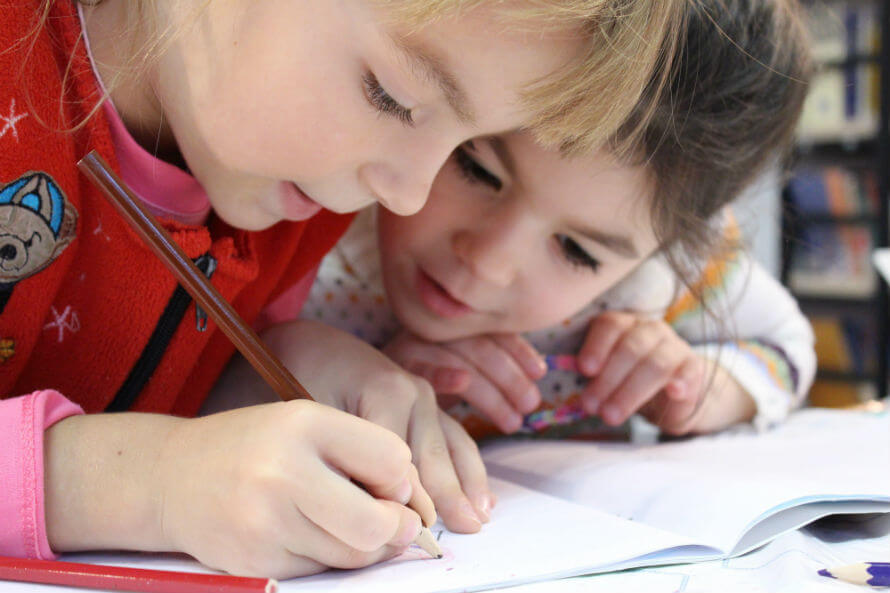Two happy young girls doing homework together