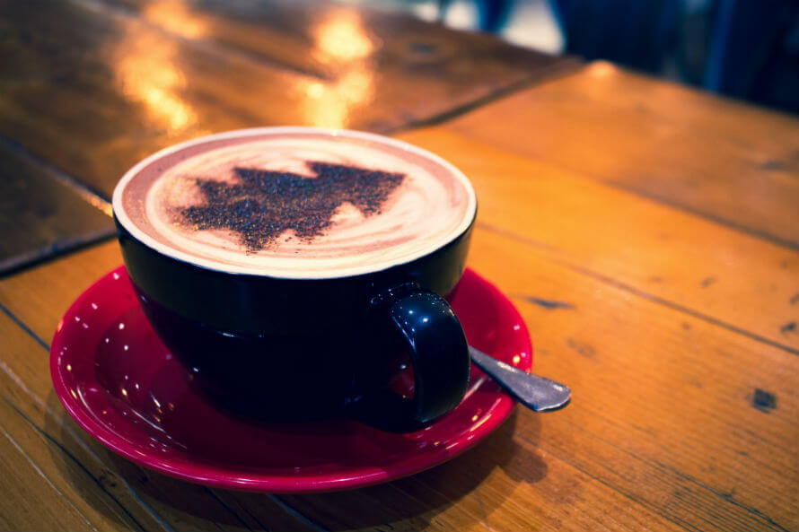 Milky coffee with Christmas tree pattern in cocoa powder