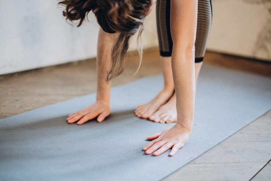 Woman on yoga mat in forward fold