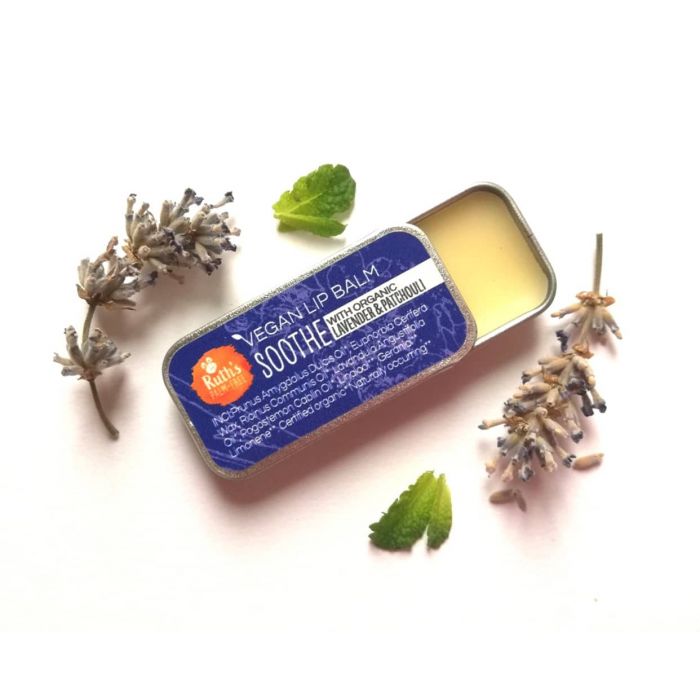 Half open tin of Ruth's lip balm surrounded by fresh lavender and mint. 