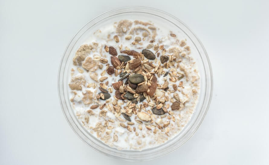 Bowl of soaked oats topped with seeds and dried fruit. 