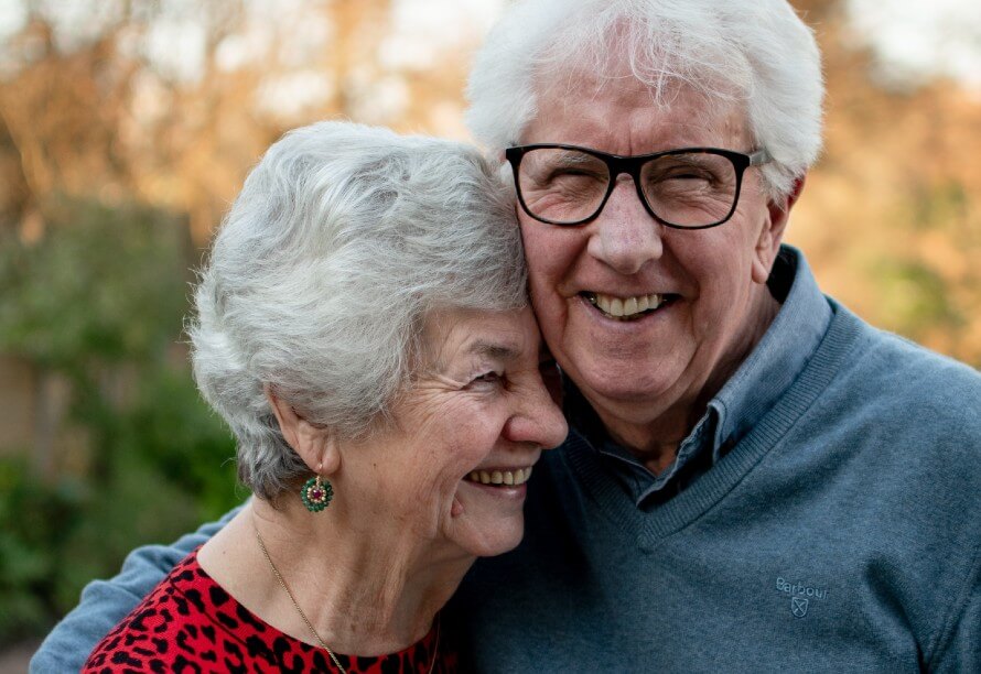 Older woman and man, smiling and hugged up to each other. 