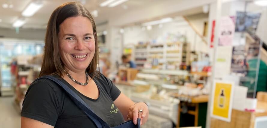 Hannah standing in Organico shop. Smiling toward camera.
