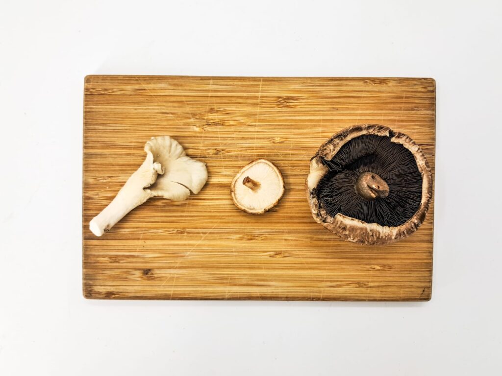 Three mushrooms on a wooden board.