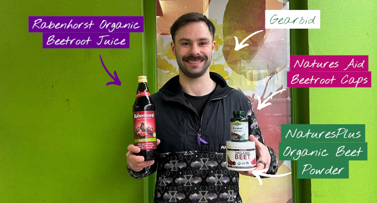 A smiling man stands in front of a bright green wall holding three beetroot products: a bottle of Rabenhorst Organic Beetroot Juice, Natures Aid Beetroot capsules, and NaturesPlus Organic Beet Powder. Text labels point to each product, and another label identifies him as “Gearoid.”
